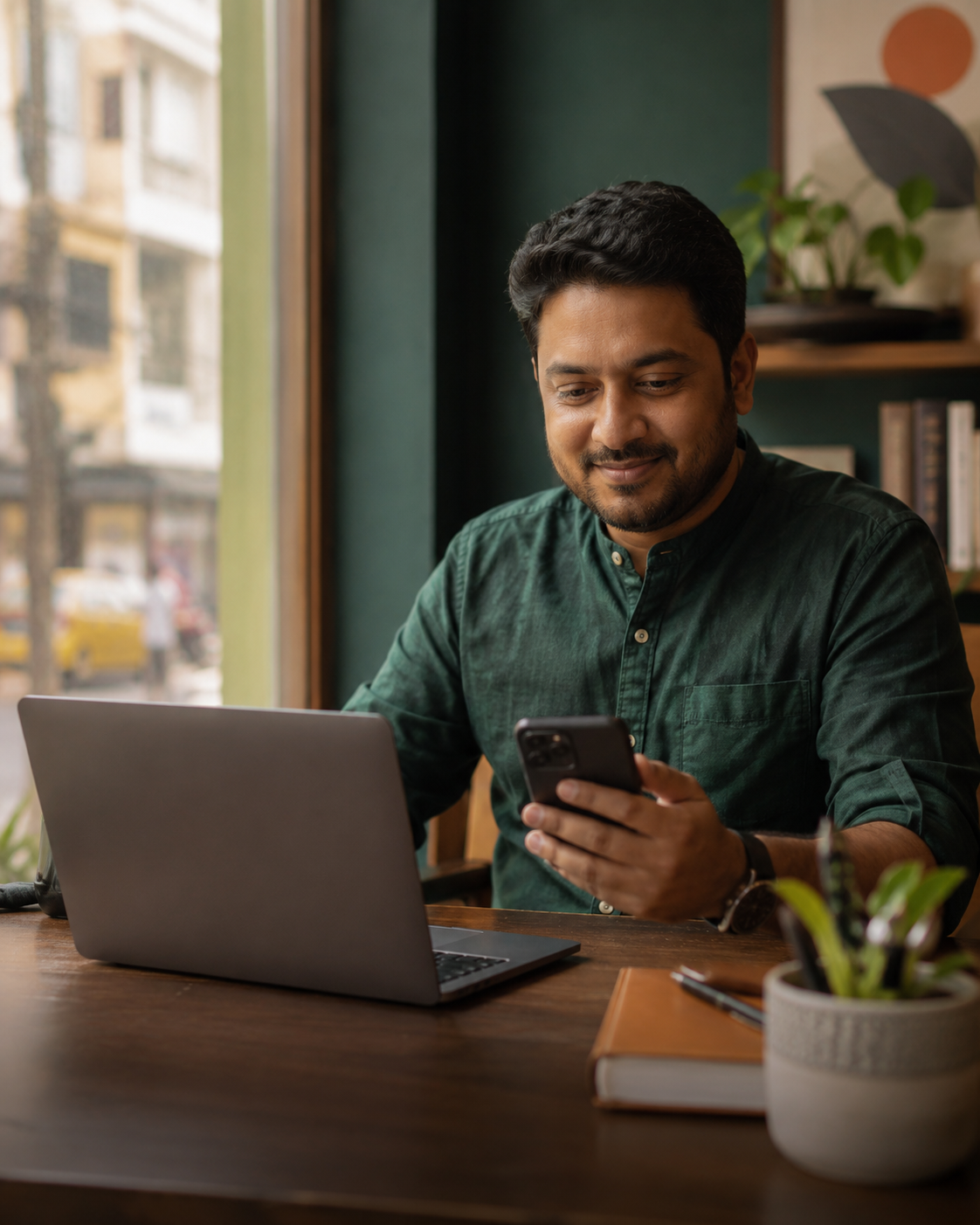 Indian local business owner managing online enquiries on a laptop and phone